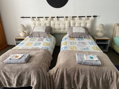 Chambre Hellébore en configuration deux lits 80, couvre-lits assortis et serviettes pliées.