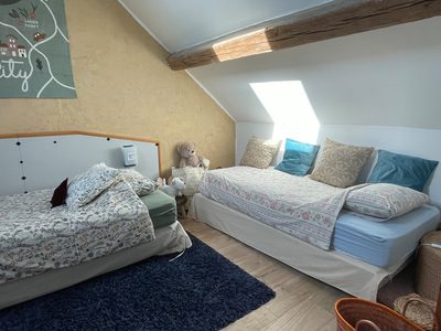 Chambre communicante de Sapin : grand lit sous rampant, banquette au pied et fenêtre de toit.